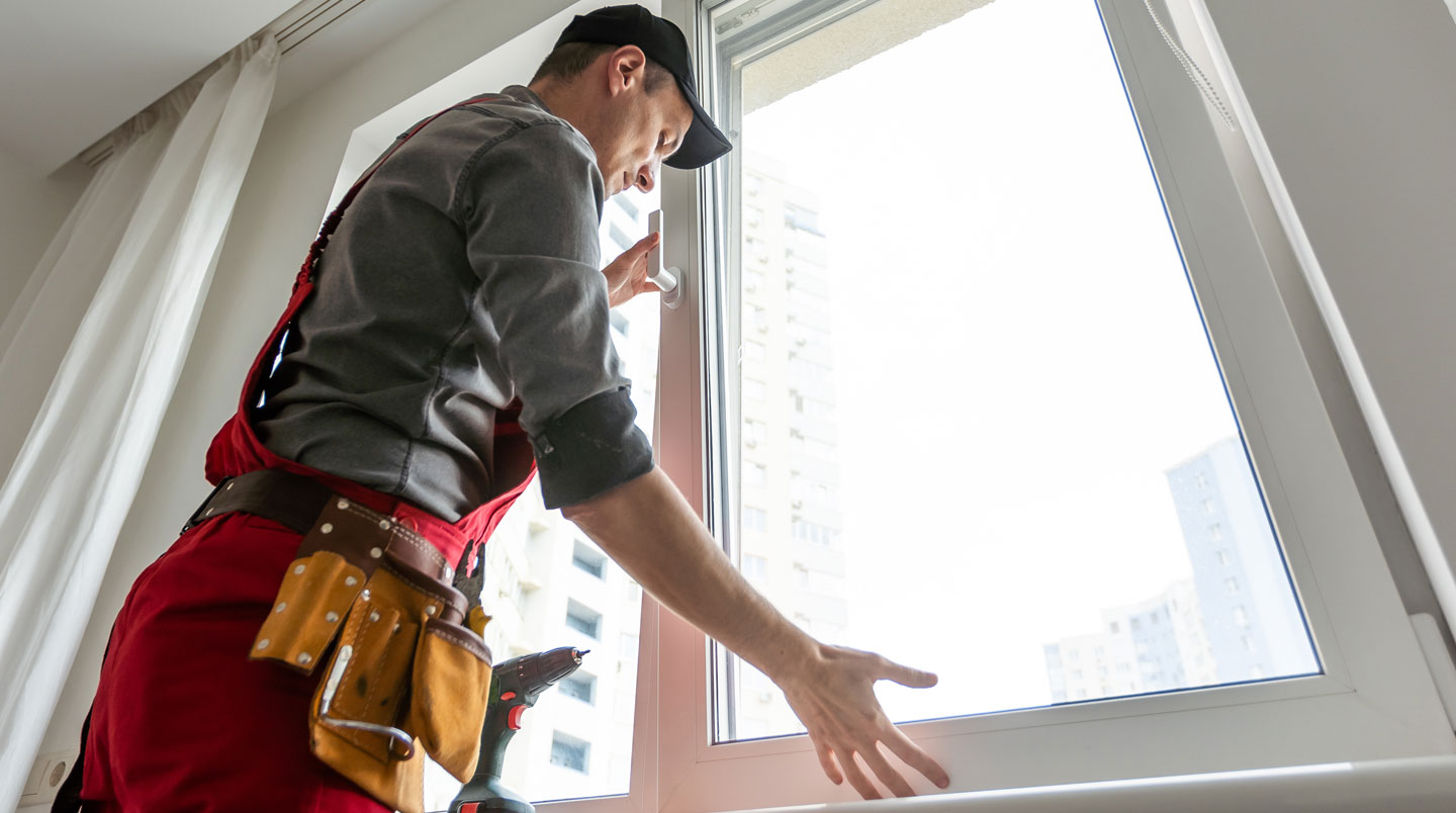 Artisan installant une fenêtre double vitrage ou de l'isolation thermique dans un logement français en rénovation énergétique, lumière naturelle, chantier propre